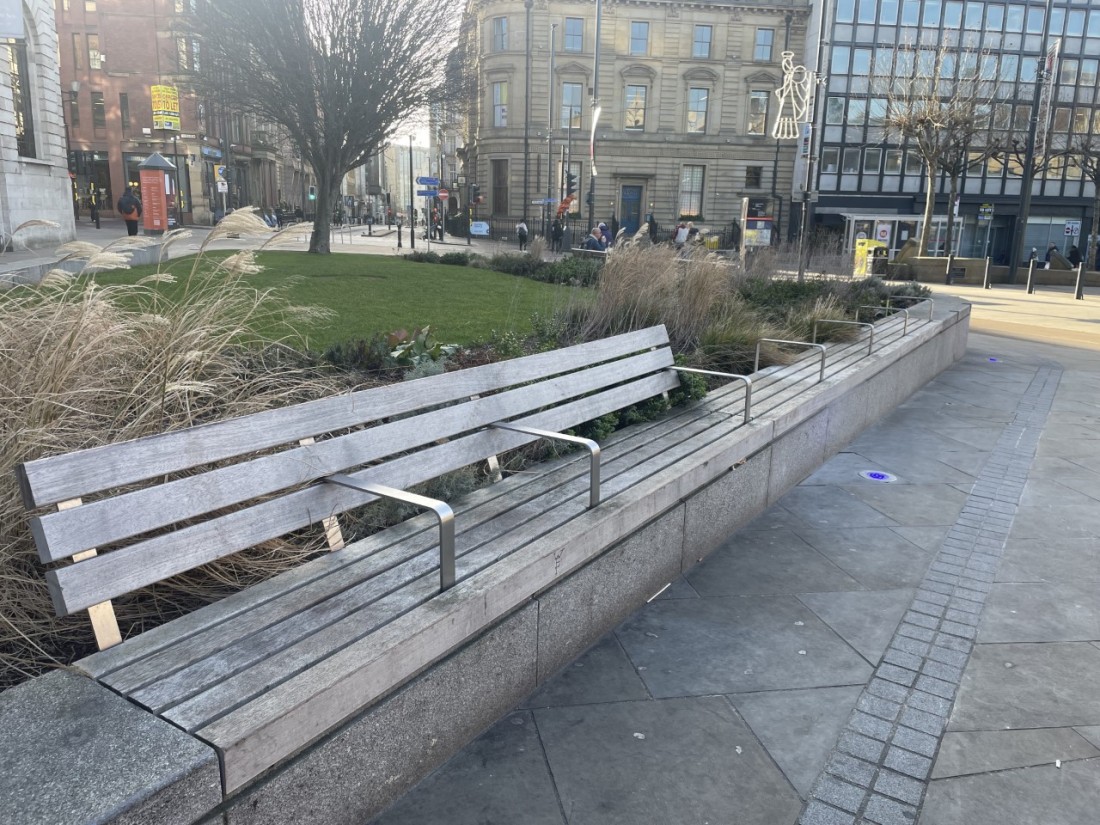 Another angle of the anti-homeless benches with white handles splitting the bench up